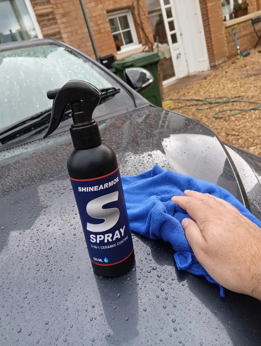 Customer photo: ShineArmor bottle on the hood of a gray car in a driveway, water beading